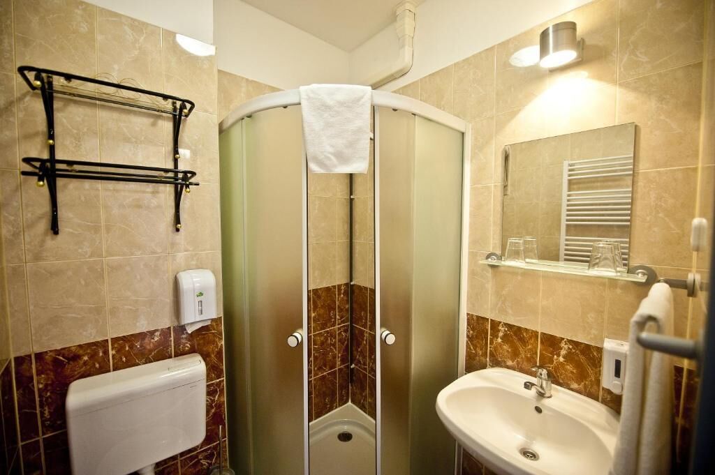 Une salle de bain avec une douche à parois de verre, un lavabo blanc, un porte-serviettes et un miroir.