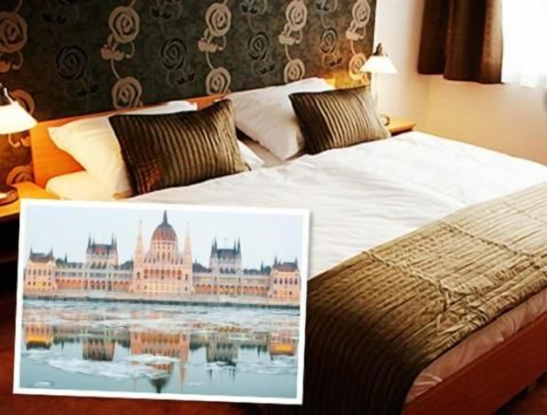 Habitaci ón de hotel con cama, almohadas, lámpara y un cuadro del parlamento de Budapest.
