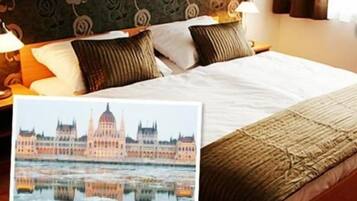 Habitación de hotel con cama, almohadas, lámpara y un cuadro del parlamento de Budapest.