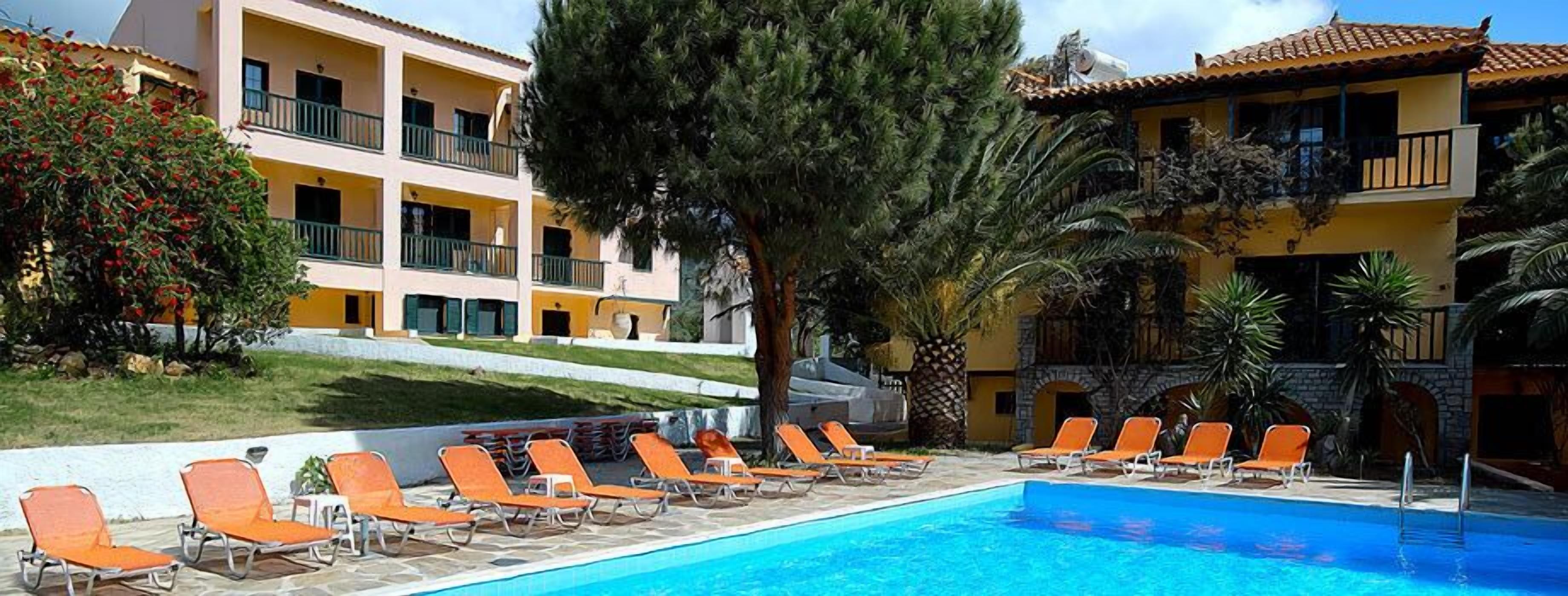Un área de piscina con sillones de descanso y un edificio con balcones.