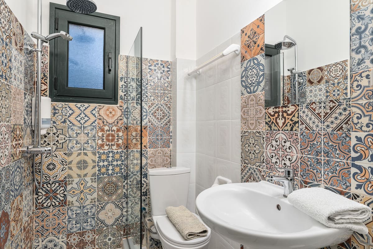 A bathroom with a shower, toilet, and sink, featuring patterned tiles.