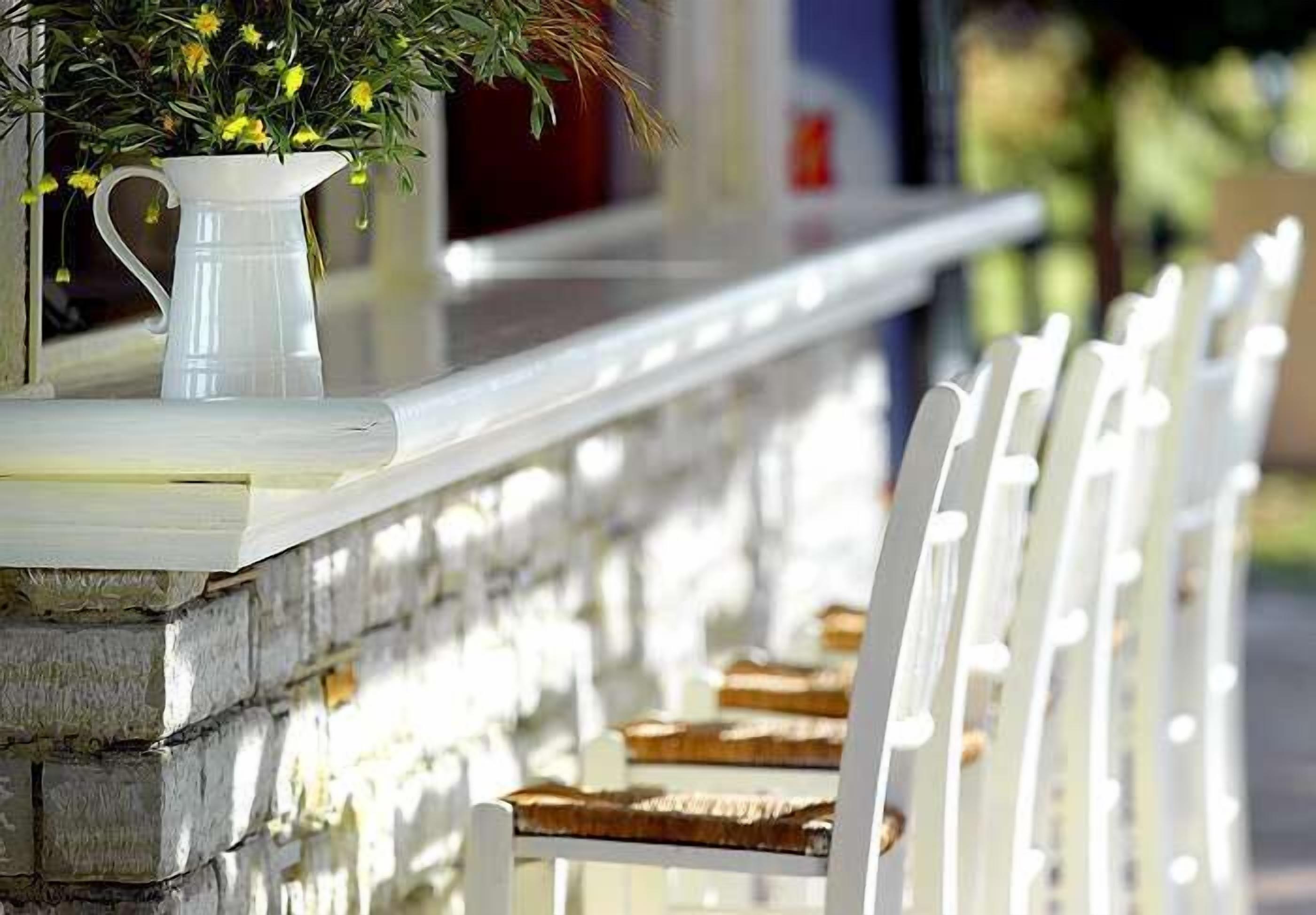 A white outdoor seating area with a stone wall and wooden benches.