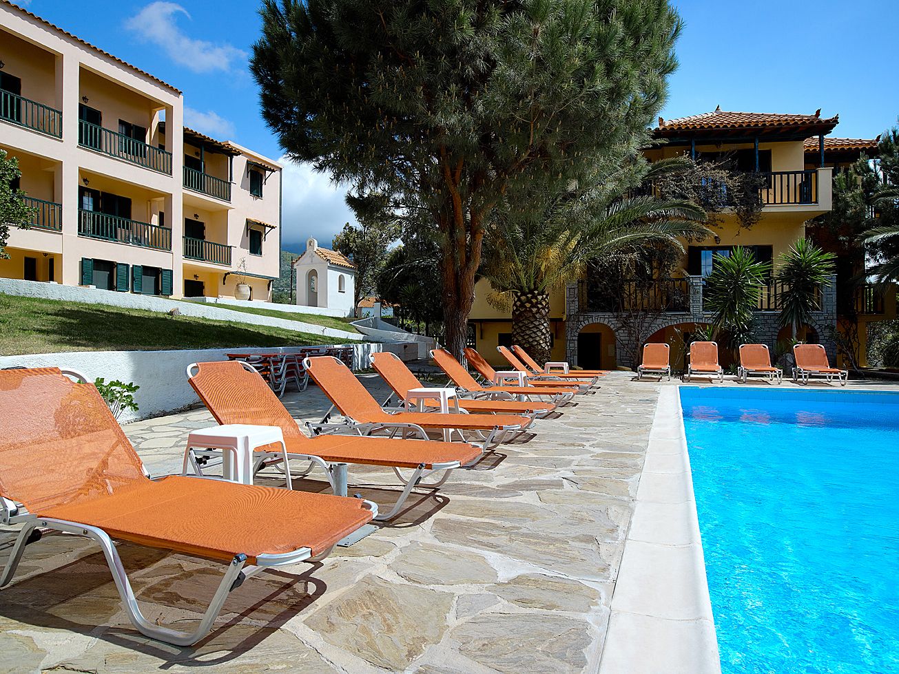 A poolside area with lounge chairs and a clear blue pool.
