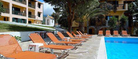 A poolside area with lounge chairs and a clear blue pool.