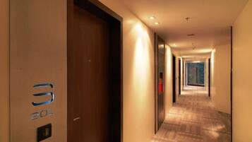 A hotel hallway with a wooden door marked "301" and a patterned carpet.