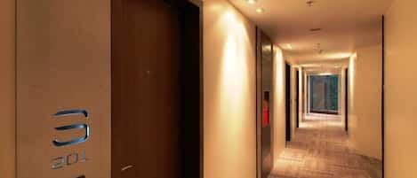 Un pasillo de hotel con una puerta de madera marcada con el número 301 y una alfombra estampada.