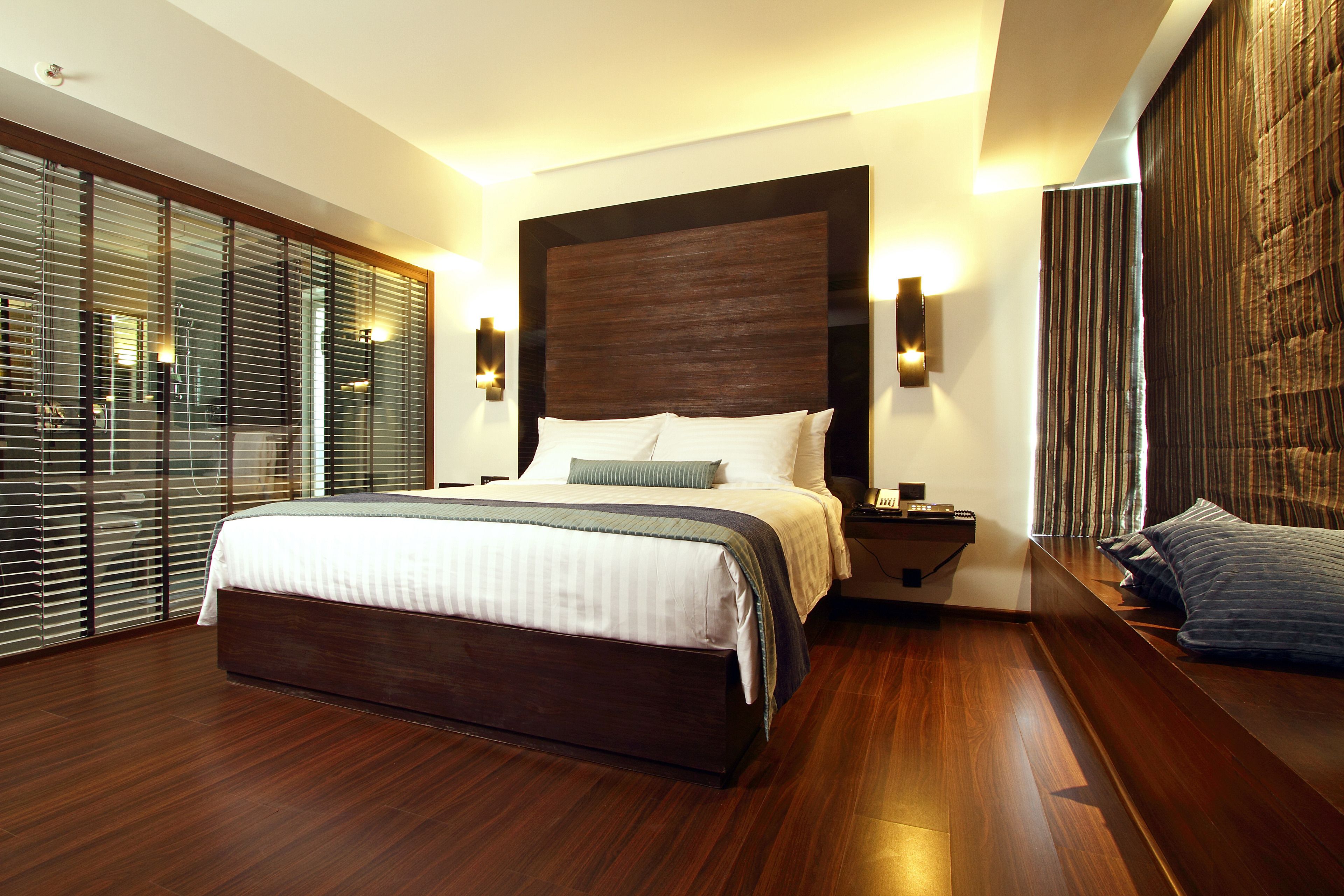 Une chambre à coucher moderne avec un grand lit, une tête de lit en bois et un banc intégré au pied du lit.