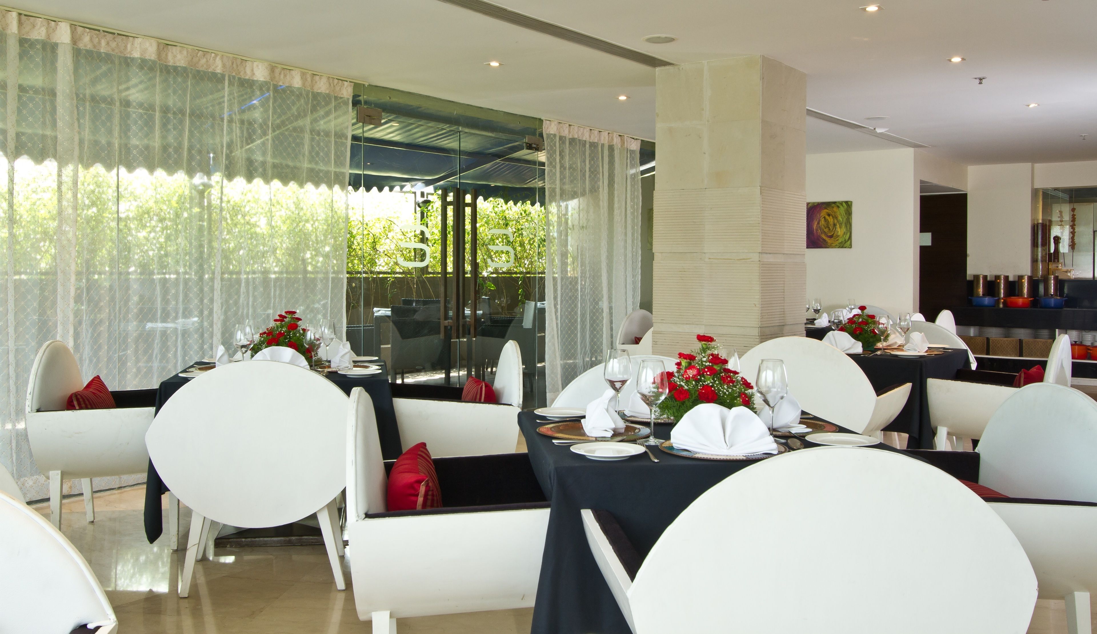 A dining area with tables set for a meal, featuring white chairs and black tablecloths.