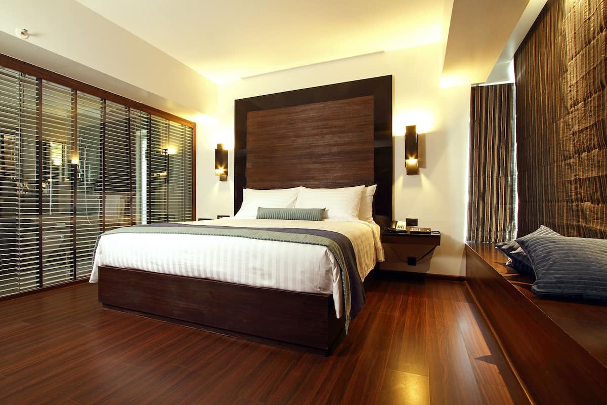 Un dormitorio moderno con una cama grande, suelo de madera, una mesita de noche y vistas a través de persianas del suelo al techo.