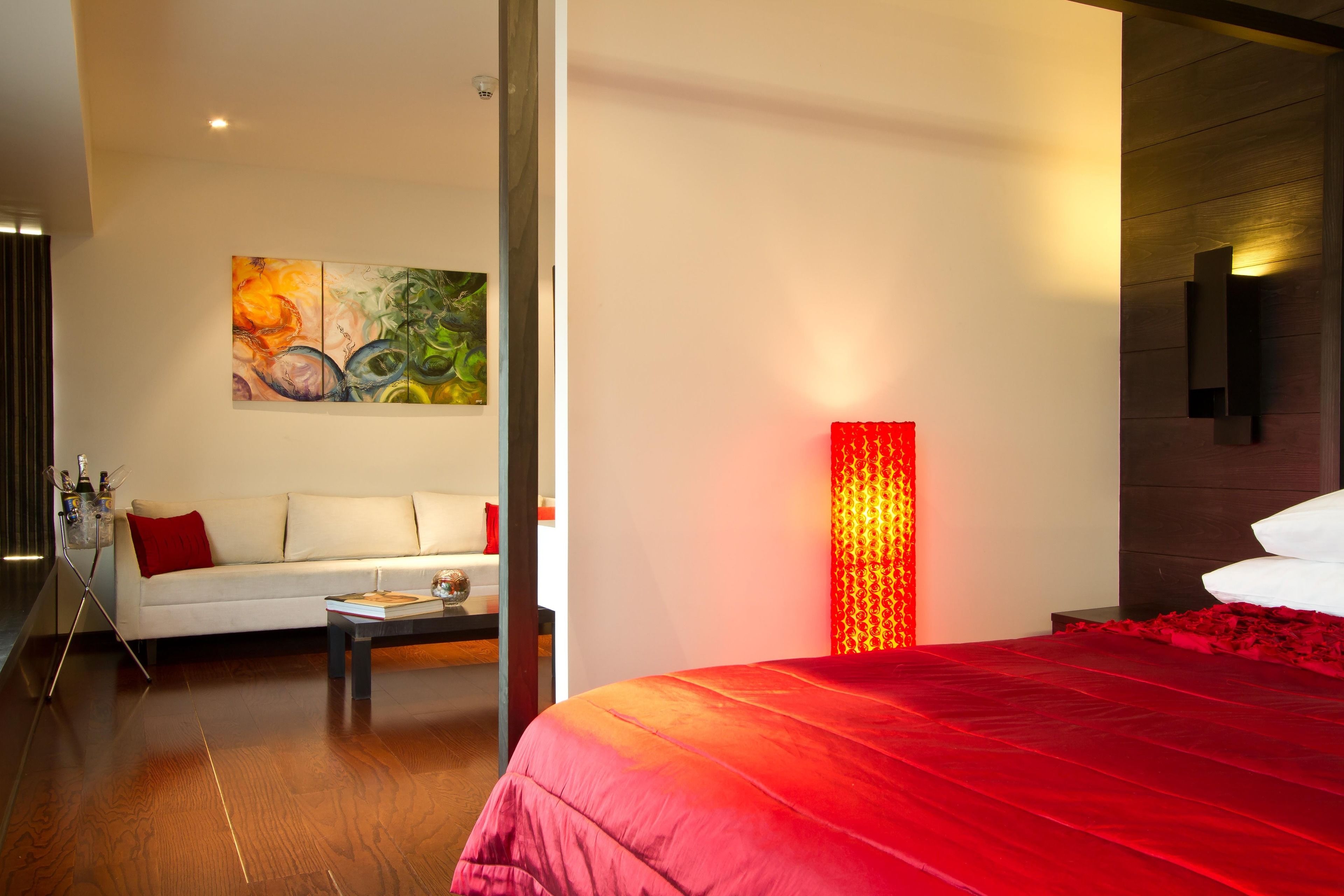 Ein modernes Hotelzimmer mit einem großen Bett, einem weißen Sofa, einem Couchtisch und einem Gemälde an der Wand.