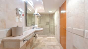 Un baño moderno con un tocador doble lavamanos, una cabina de ducha de cristal y una puerta de madera.
