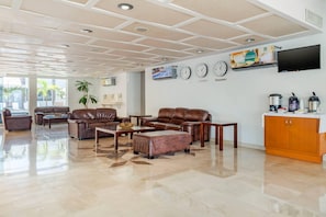 A spacious living area with leather sofas, a coffee table, a TV mounted on the wall, and a kitchen area with appliances. - Quality Inn Mazatlan (Mazatlán)