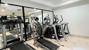 Un gimnasio con cintas de correr, elípticas y equipos de pesas.