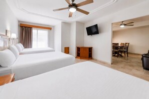 A hotel room with two beds, a TV, a ceiling fan, a small wooden cabinet, and a dining area with chairs and a table. - Quality Inn Mazatlan (Mazatlán)