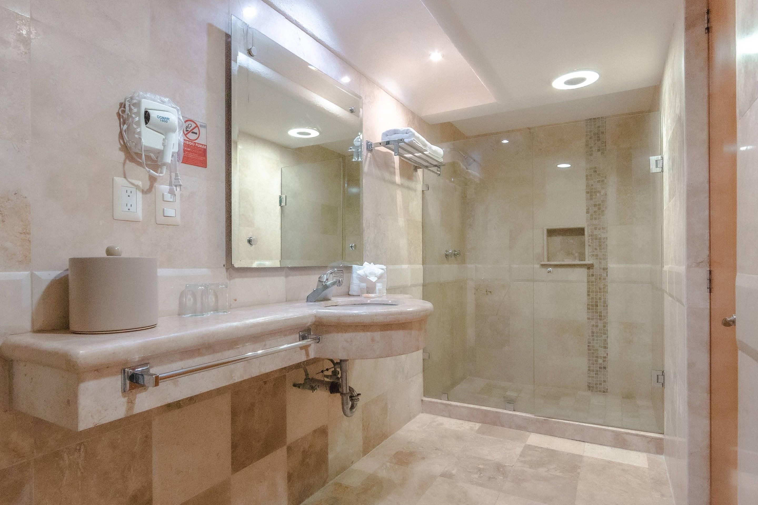 A modern bathroom with a glass-enclosed shower, a large mirror, and a vanity with a towel rack.