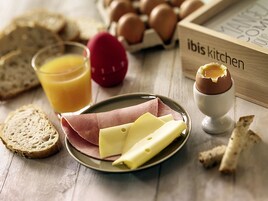 A breakfast setting with bread, eggs, cheese, and a glass of orange juice on a wooden table.