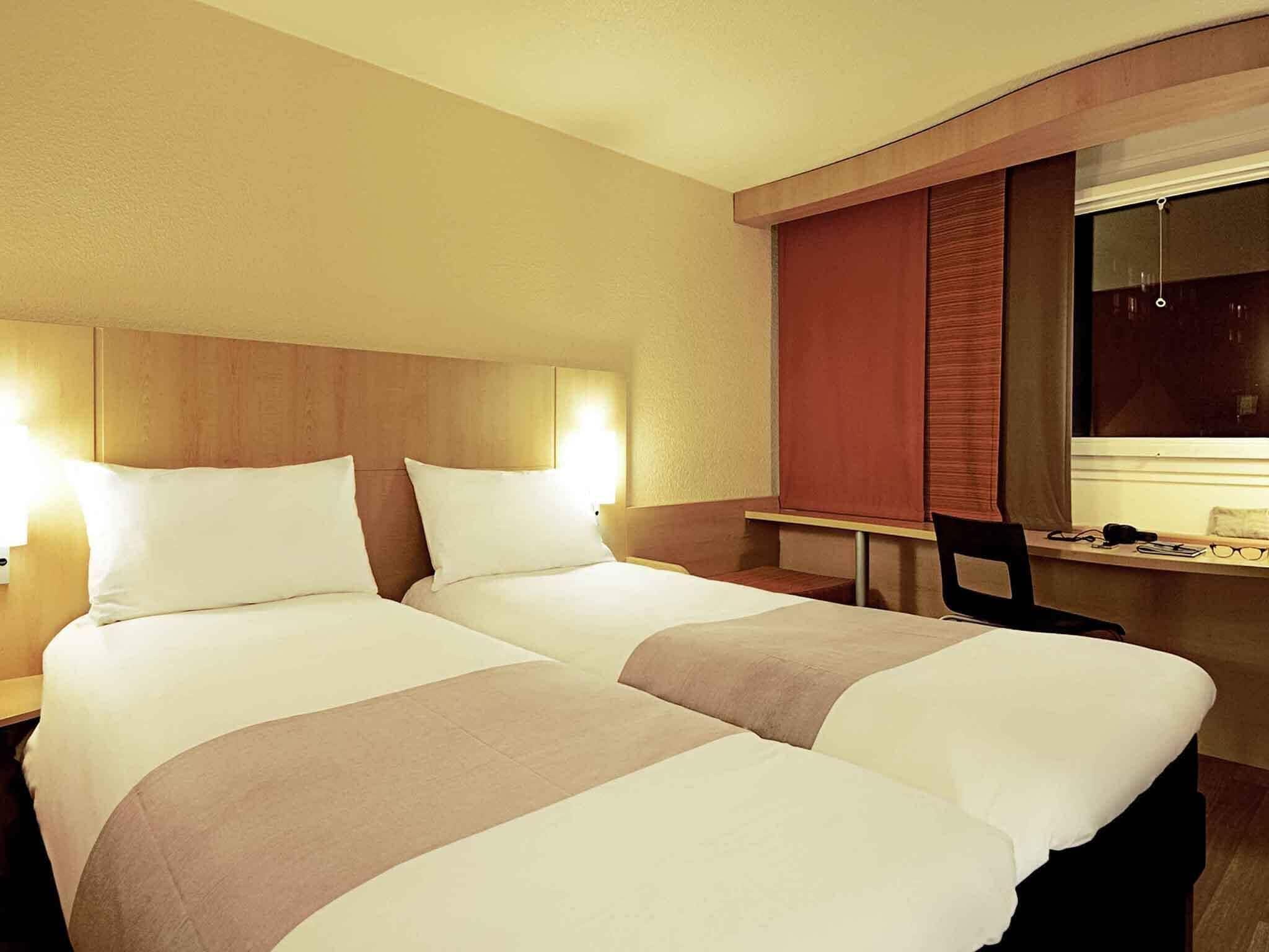 Une chambre d’hôtel avec deux lits, un bureau et une chaise.