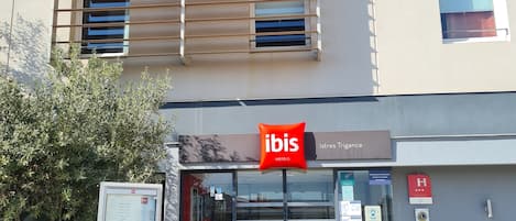 A modern building with a sign for ibis hotels.