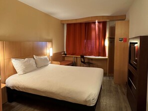 A hotel room with a bed, desk, chair, and a television. - ibis Istres Trigance (Istres)