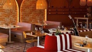 Interior de restaurante com cabines, mesas e luminárias pendentes.