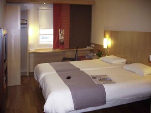 Una habitación de hotel con cama, escritorio y silla.