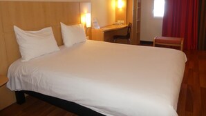 Quarto de hotel com uma cama grande, uma mesa e uma cadeira.