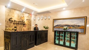 A reception desk with a sign for Saigon Hotel, a wall clock, and a framed landscape painting. - Sanouva Saigon Hotel (Ho Chi Minh City)