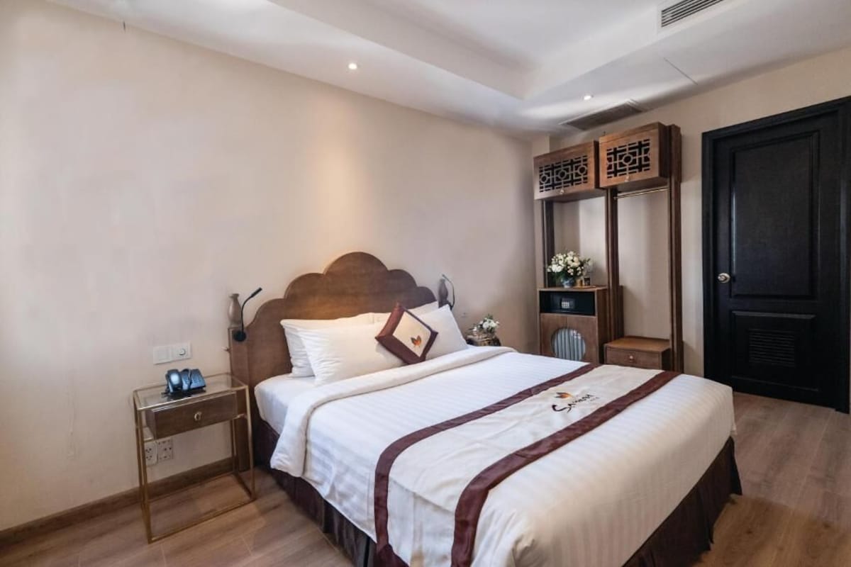 Une chambre d’hôtel avec un lit, une table de chevet et une armoire.