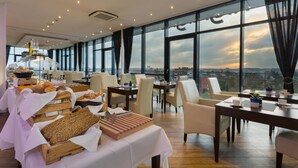 Un comedor amplio con techo alto y ventanas grandes que ofrecen vistas a la ciudad.