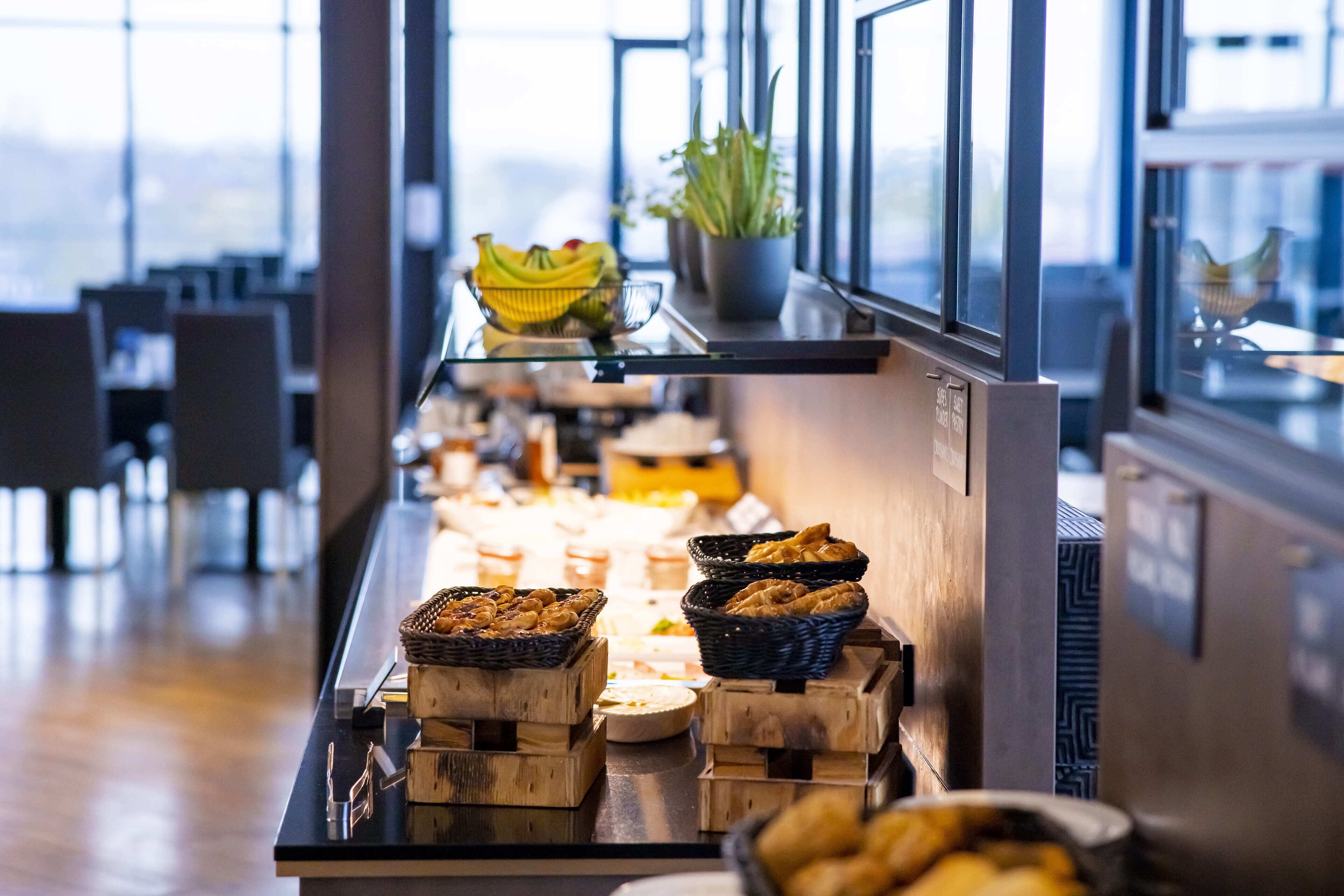 A buffet setup with various food items and a potted plant on a shelf.