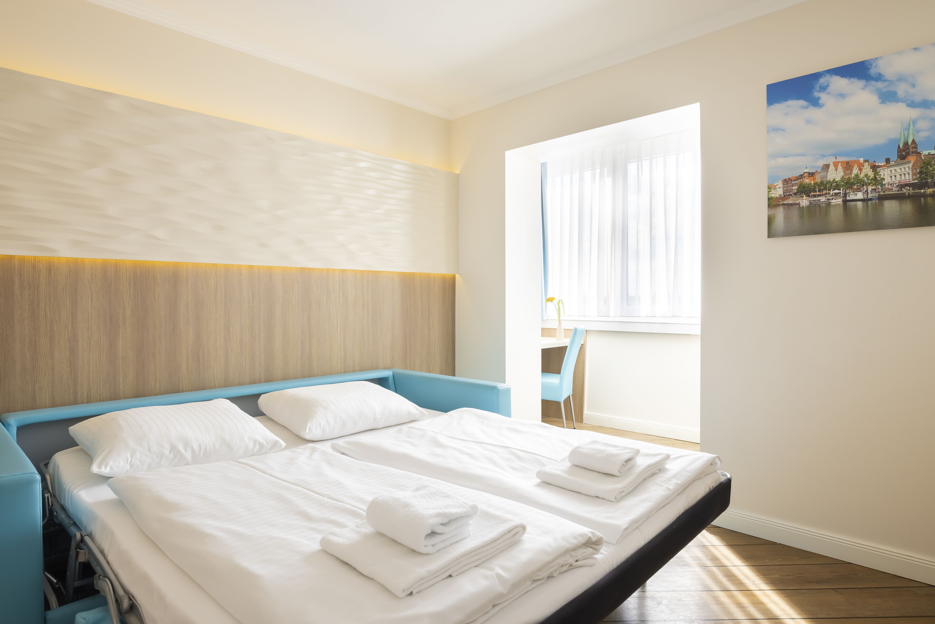 A hotel room with a bed, a desk, and a chair.