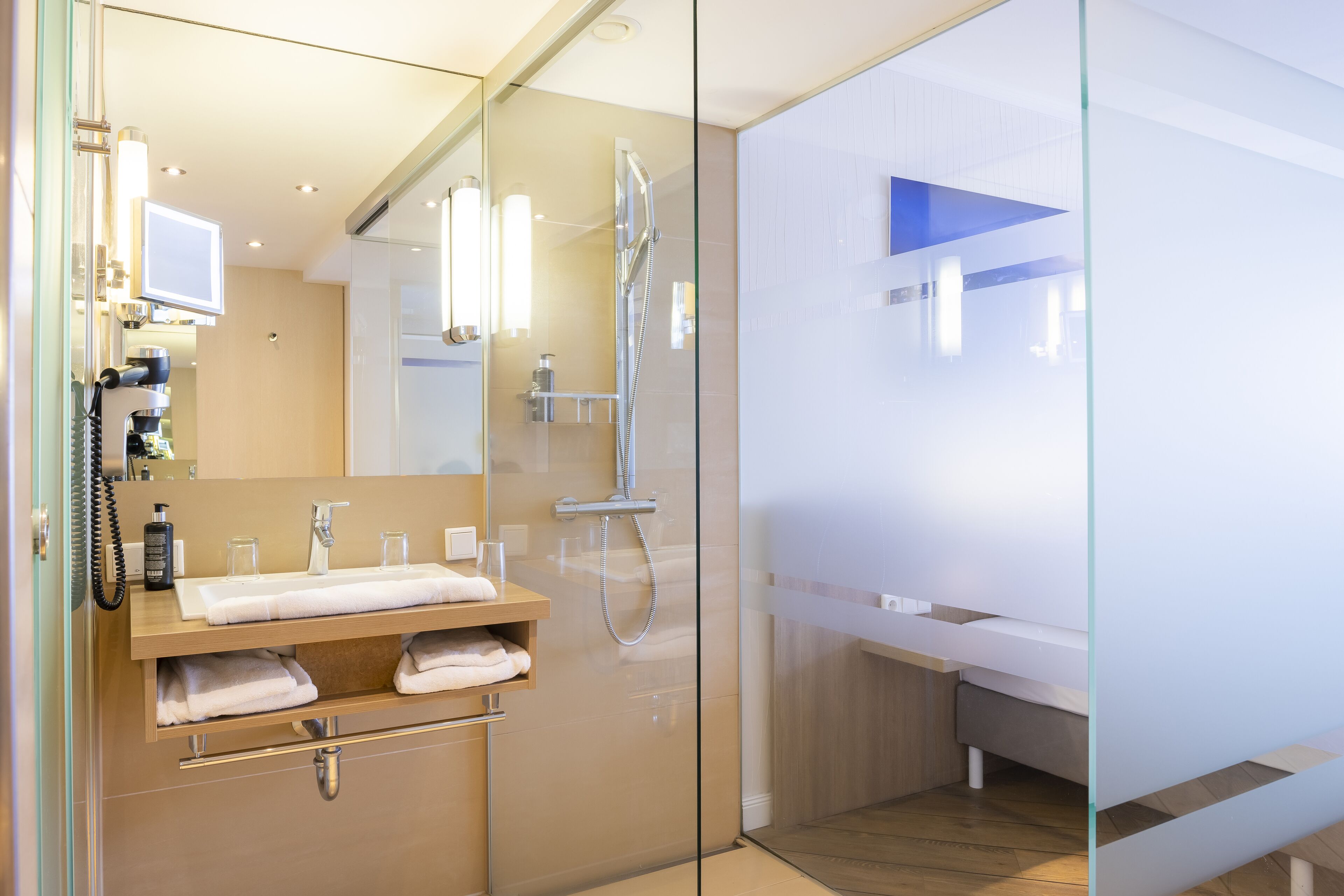 Un baño moderno con ducha de vidrio, tocador con espejo y lavamanos.