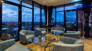 Habitación de hotel moderna con ventanas amplias, asientos cómodos y vistas de la ciudad.