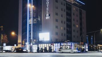 Een meerhoog hotel met een opvallend 'HOTEL' bord, een 'highlight' bord bovenaan en een groot verlicht reclamebord op straatniveau.