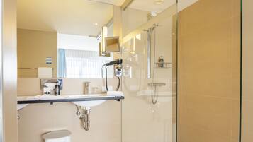 A modern bathroom with a glass shower enclosure, a vanity with a sink, and a mirror.