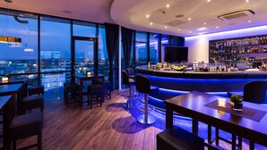 Un moderno bar con una barra curva, taburetes y una amplia selección de botellas en estanterías.