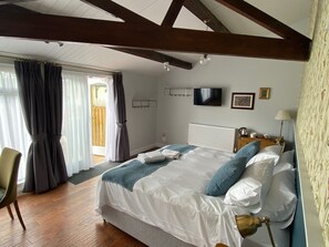 A bedroom with a bed, a chair, a TV, a radiator, and a lamp.