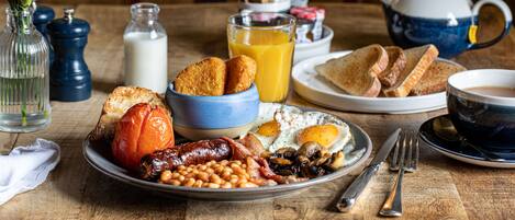 A breakfast table with a variety of foods including toast, eggs, beans, and sausages.