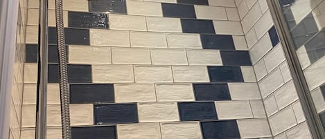 A shower area with a tiled wall and a glass shower enclosure.