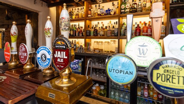 A bar with various beer taps and a well-stocked liquor shelf. - The New Inn (Crediton)