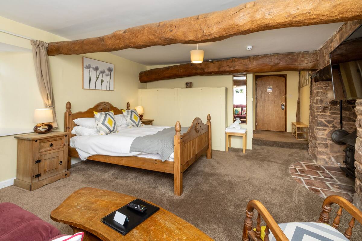 Um quarto aconchegante com uma cama de madeira, mesa de cabeceira, escrivaninha e lareira de pedra.
