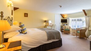 A hotel room with a large bed, bedside lamps, a desk with a chair, a television, and a window with curtains.