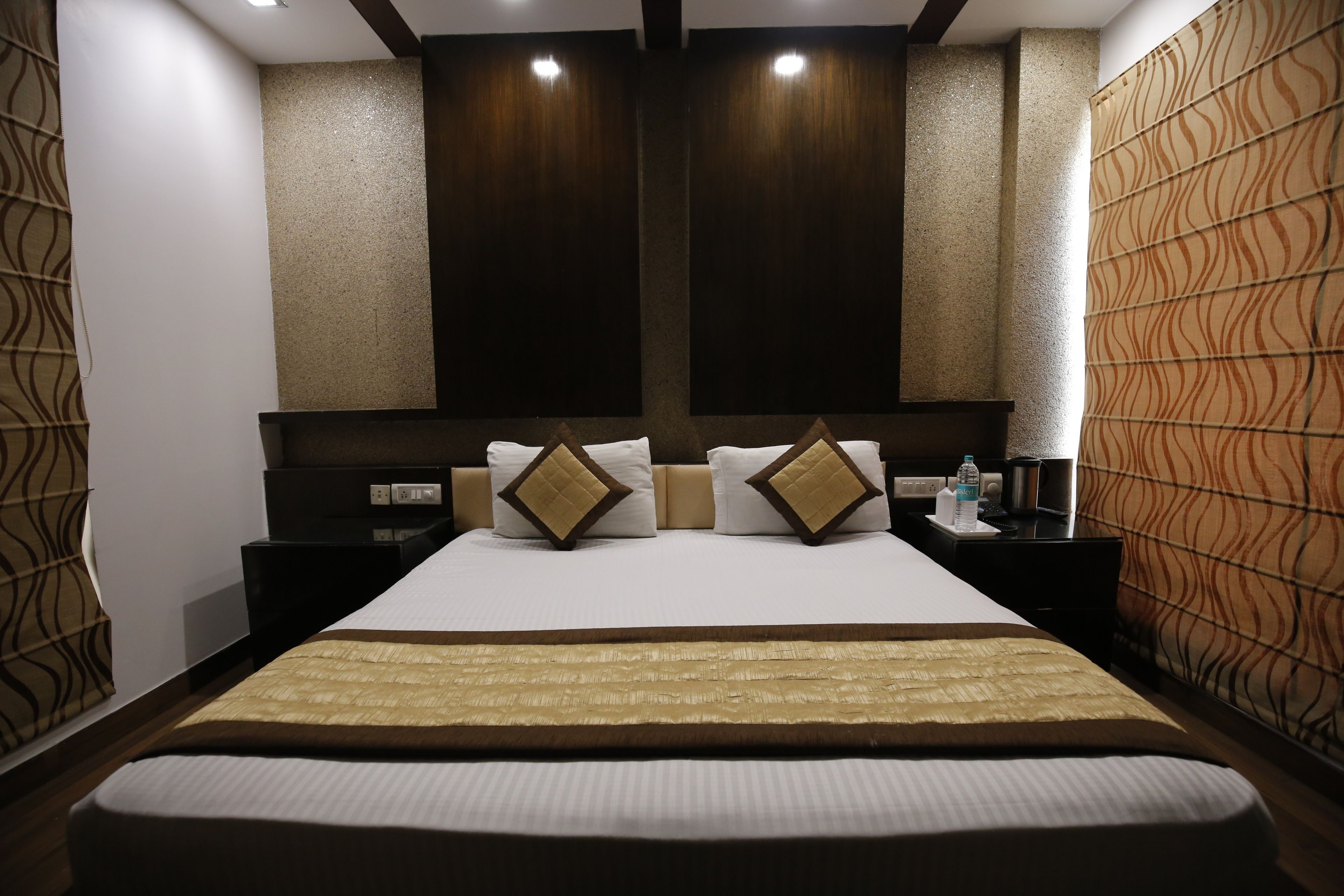 Une chambre d’hôtel avec un grand lit, deux tables de chevet, une petite table et un mur décoré d’un motif.