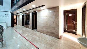 A modern hotel corridor with marble flooring, a red line marking, and a series of doors. - Hotel Delhi Pride (New Delhi)