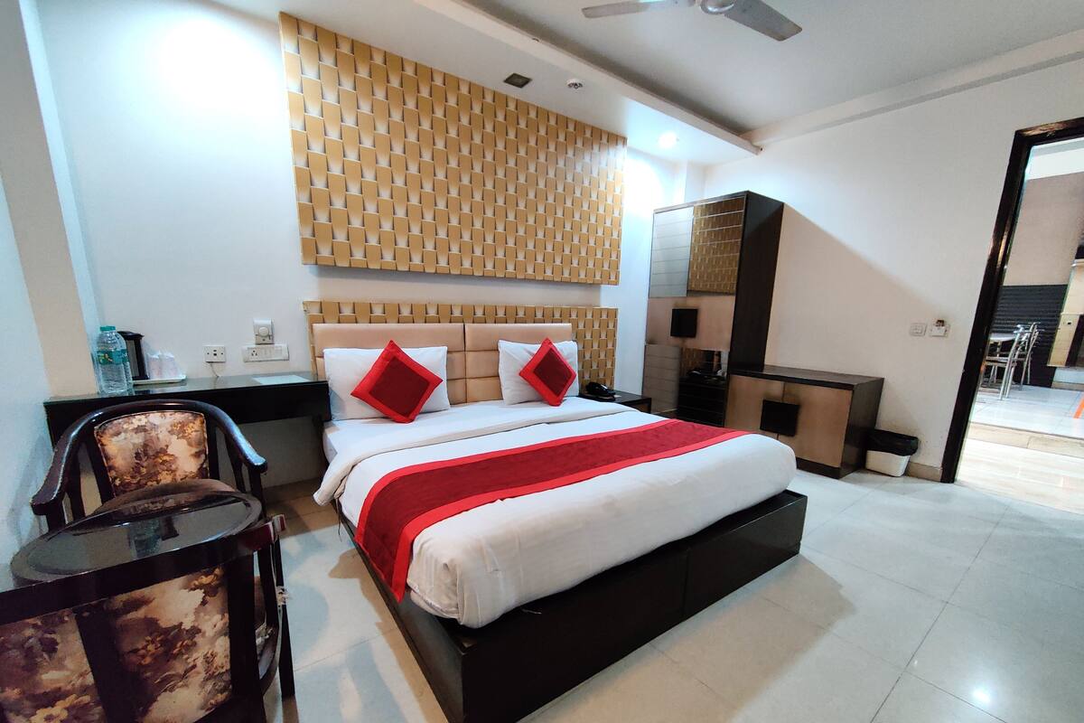 A modern hotel room with a large bed, a desk, and a chair.