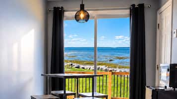 Un balcon avec vue sur la mer, un luminaire suspendu et une petite table avec des chaises.