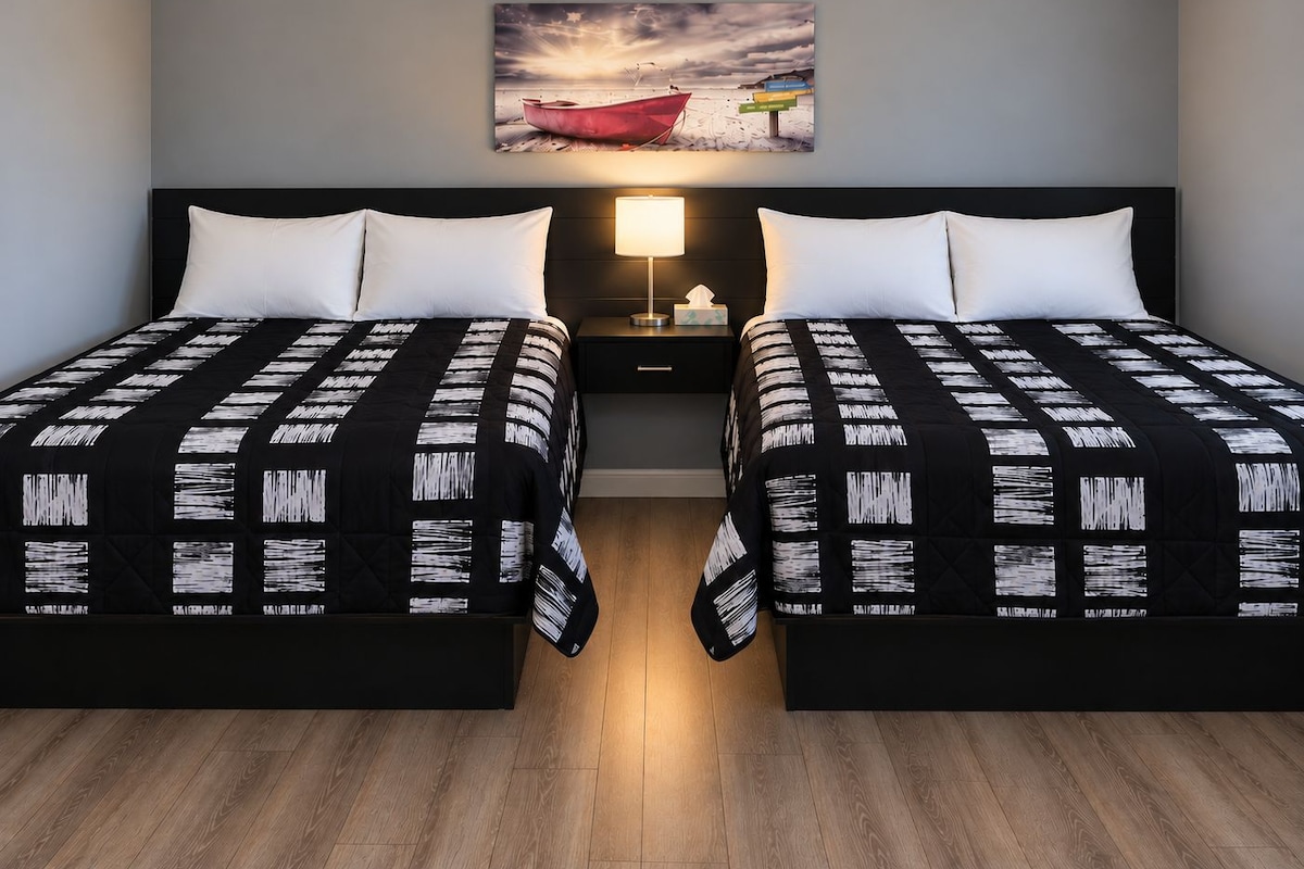 A double bed room with a nightstand, a lamp, and a painting of a boat on the wall.