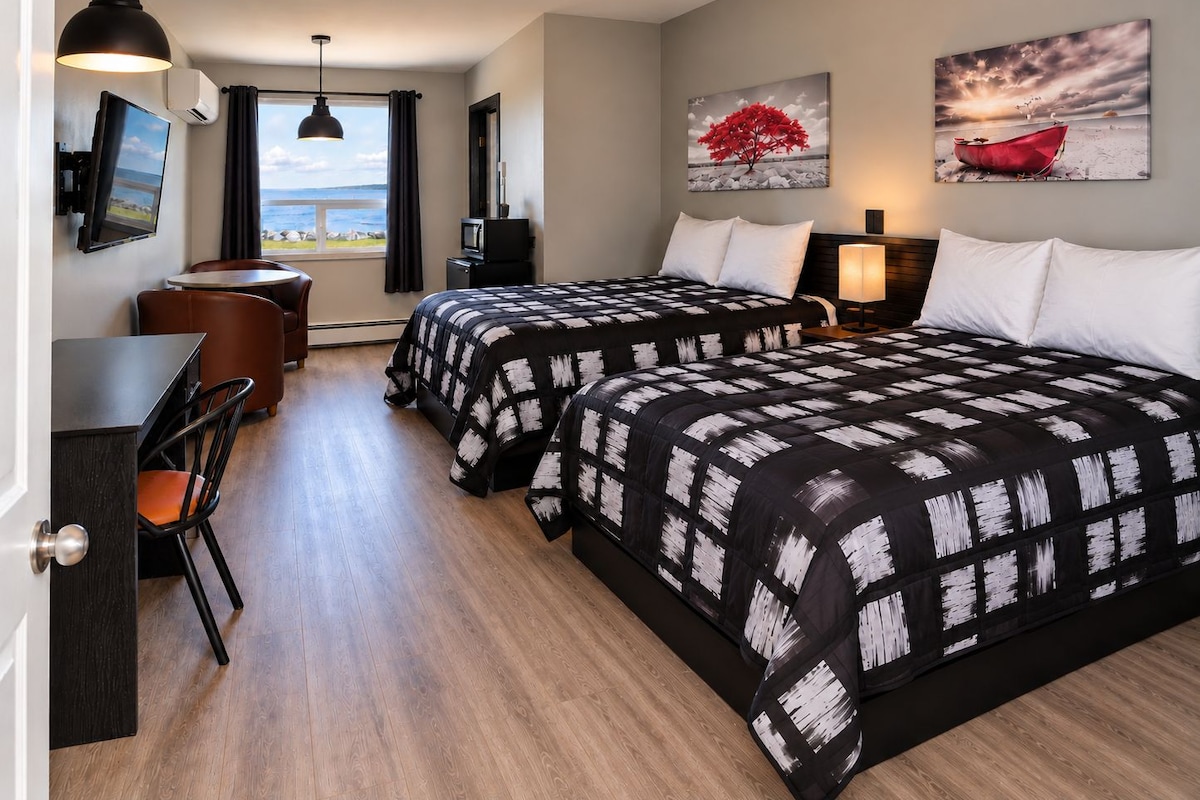 A hotel room with two beds, a desk, and a chair.
