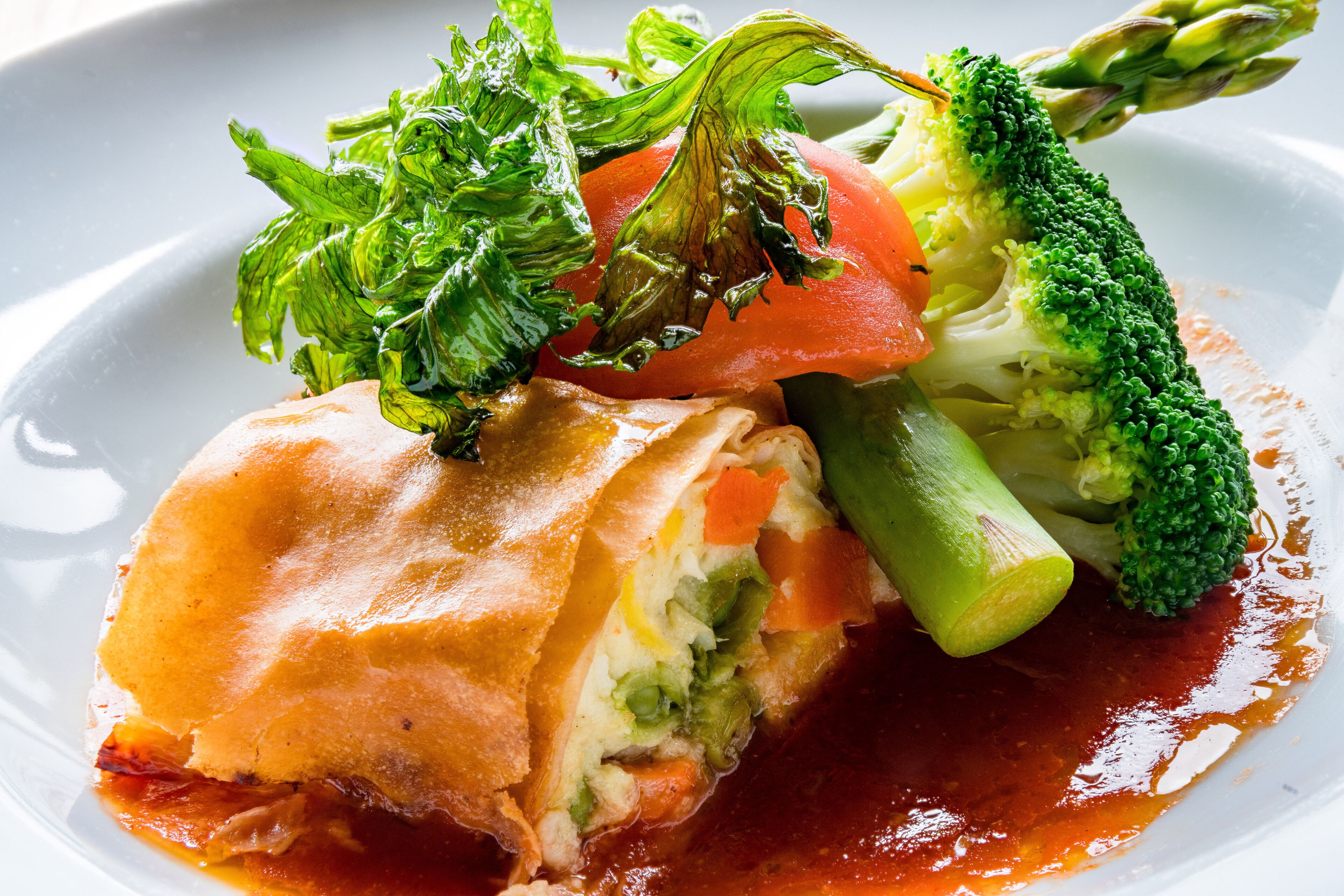 A dish with a pastry base, vegetables, and sauce.