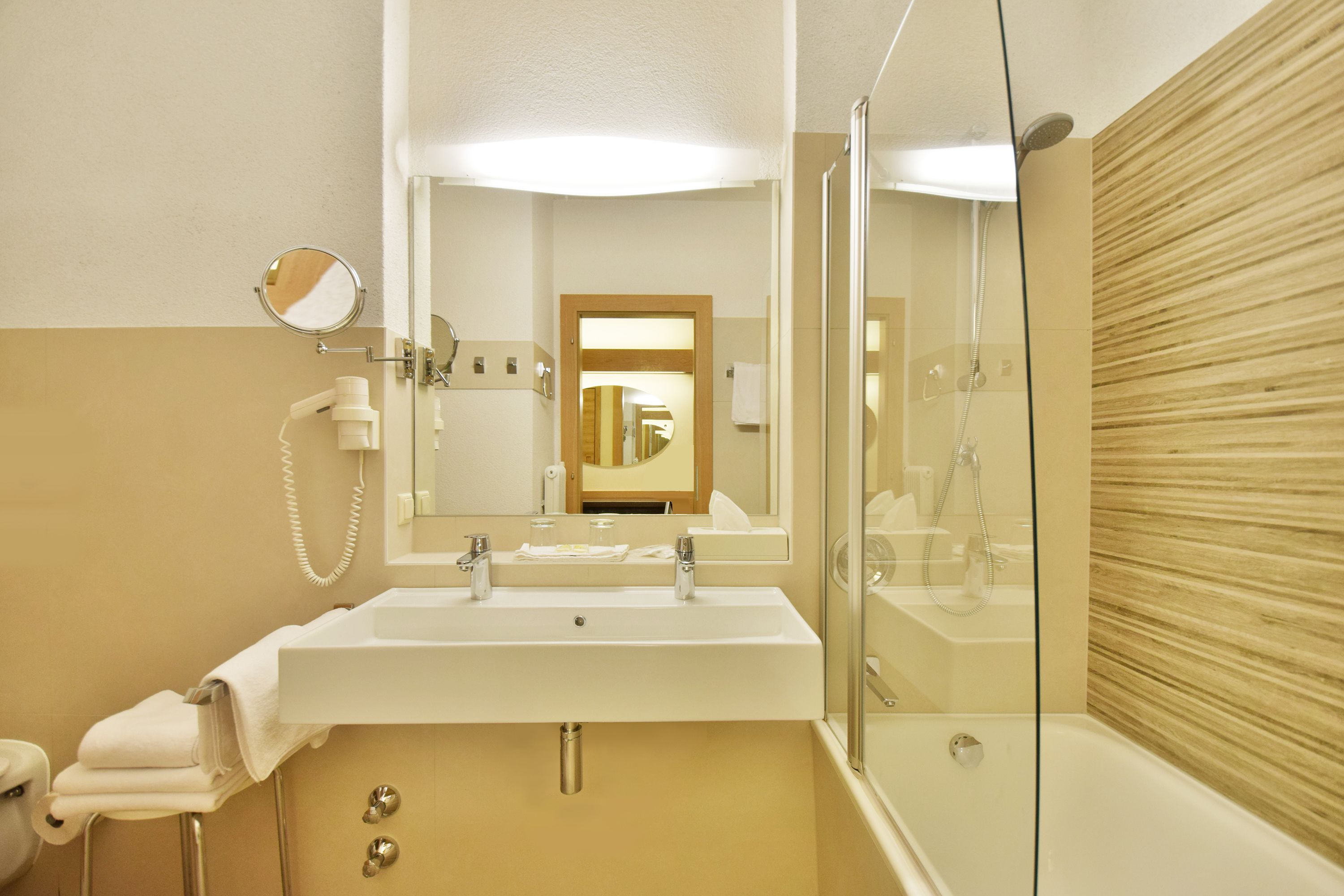 A bathroom with a sink, mirror, and shower.